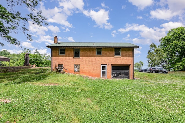 rear view of property featuring a chimney, a garage, a lawn, and brick siding