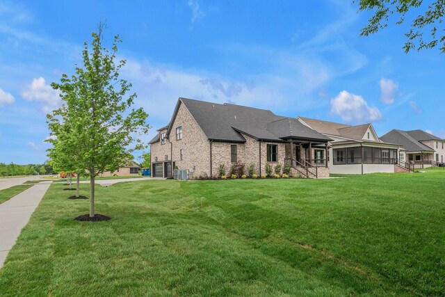 848 Brook Trl, Lebanon, TN 37087 - view of front of house featuring a sunroom, an attached garage, a front lawn, central AC unit, and brick siding