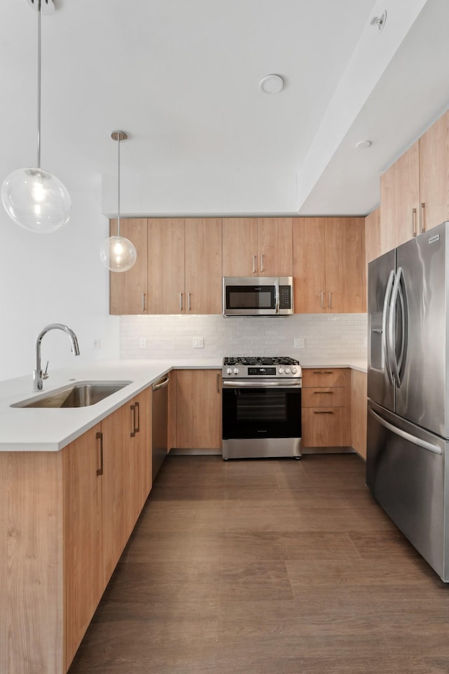 kitchen with stainless steel appliances, a sink, light countertops, decorative backsplash, and pendant lighting