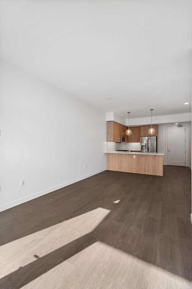 unfurnished living room featuring baseboards and dark wood-type flooring