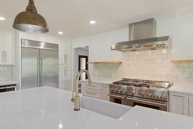 4824 Leipers Creek Rd, Williamsport, TN 38487 - kitchen with high quality appliances, wall chimney exhaust hood, white cabinetry, tasteful backsplash, and recessed lighting