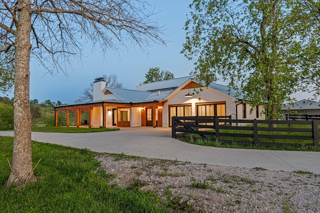 4824 Leipers Creek Rd, Williamsport, TN 38487 - modern farmhouse with curved driveway, metal roof, a chimney, a garage, and stucco siding