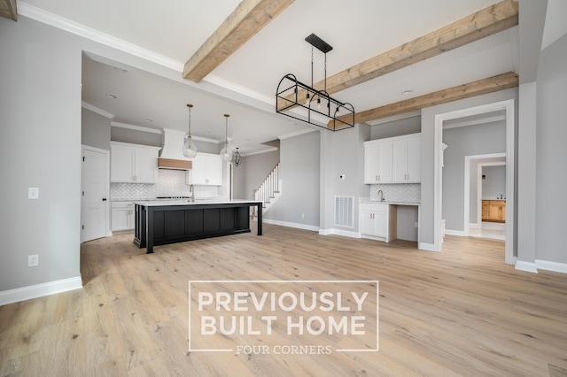 5517 Sinclair St, Murfreesboro, TN 37127 - kitchen featuring a chandelier, tasteful backsplash, white cabinetry, a kitchen island with sink, and beamed ceiling