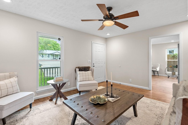 living area featuring healthy amount of natural light, light wood-style floors, recessed lighting, a ceiling fan, and baseboards