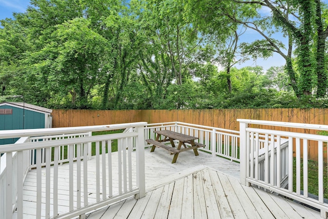 deck with a fenced backyard, a storage shed, and an outdoor structure
