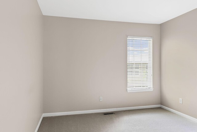 carpeted empty room featuring baseboards