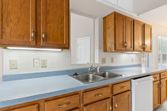 kitchen with white dishwasher, a sink, light countertops, brown cabinetry, and backsplash