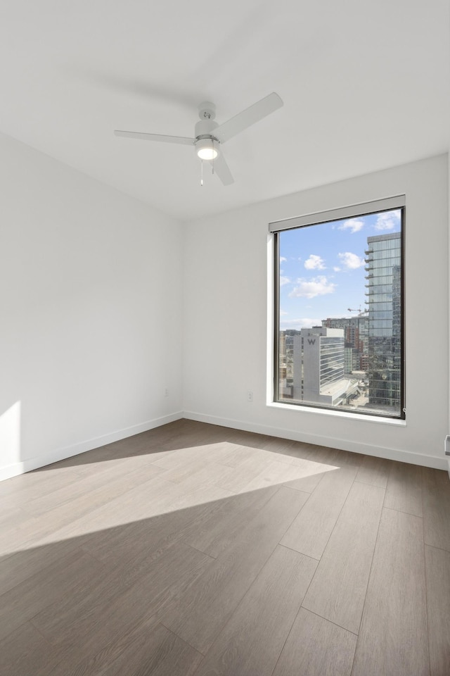 spare room featuring a ceiling fan, wood finished floors, and baseboards