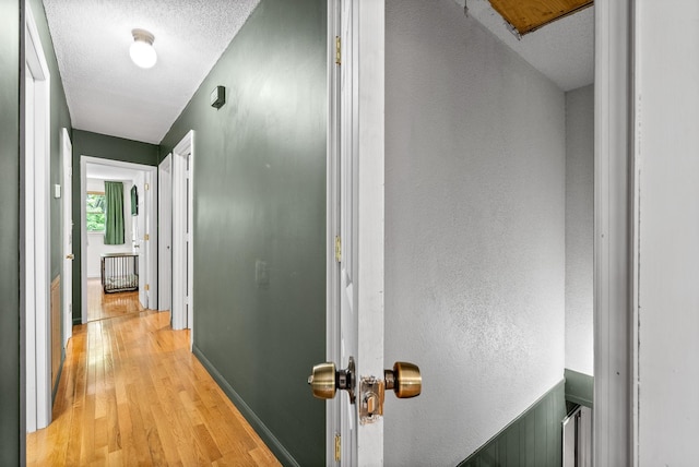 hallway featuring light wood finished floors and a textured ceiling