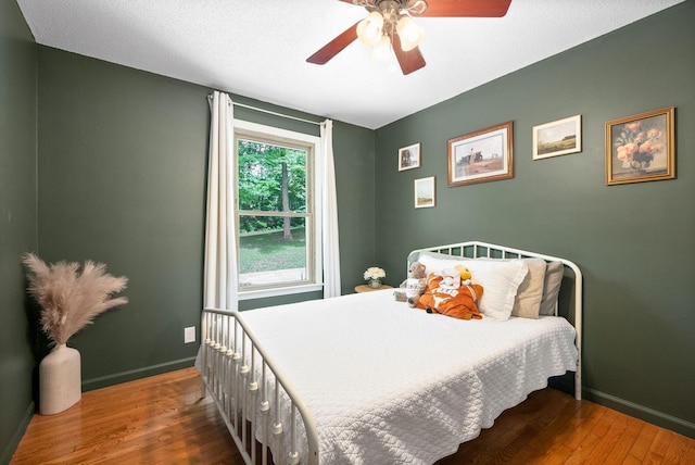 bedroom with wood finished floors, baseboards, and ceiling fan