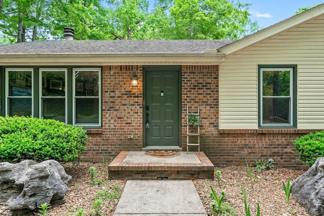 property entrance with brick siding and a shingled roof