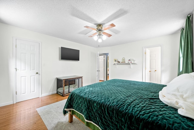 bedroom featuring wood finished floors, baseboards, a ceiling fan, and a textured ceiling
