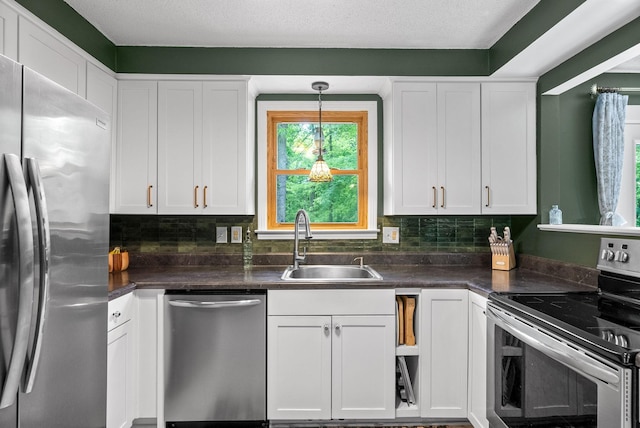 kitchen featuring stainless steel appliances, a sink, white cabinets, and dark countertops