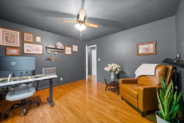 office featuring light wood-type flooring, a ceiling fan, a textured ceiling, and baseboards