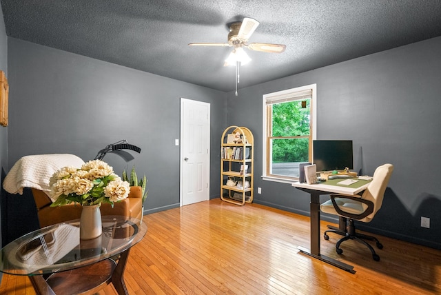 home office featuring hardwood / wood-style floors, ceiling fan, a textured ceiling, and baseboards