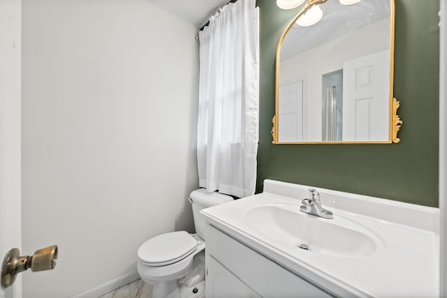 bathroom with toilet, vanity, and baseboards