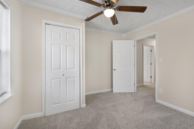 unfurnished bedroom featuring carpet floors, a closet, ceiling fan, baseboards, and crown molding