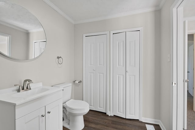 bathroom with wood finished floors, toilet, a closet, crown molding, and vanity