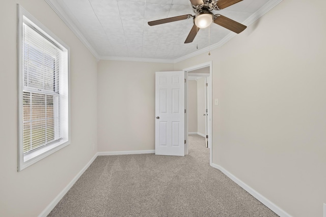 carpeted spare room with baseboards, ornamental molding, and ceiling fan
