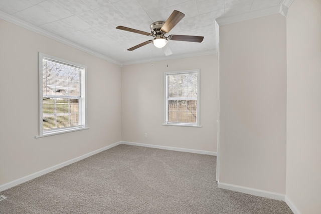 empty room with carpet, crown molding, baseboards, and a ceiling fan