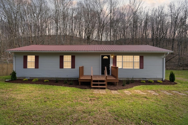 view of front of house featuring metal roof, a deck, a front lawn, and crawl space
