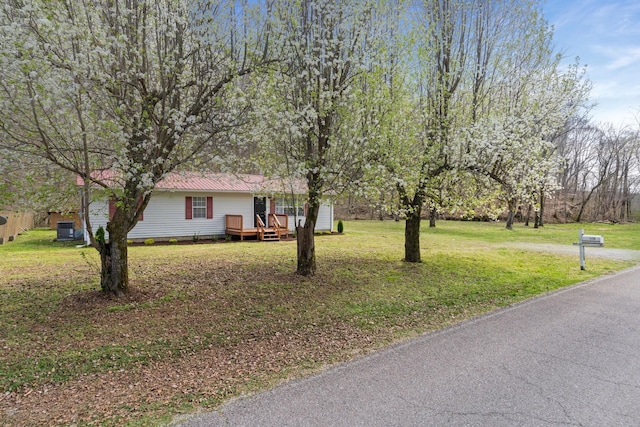 view of front of property with a front lawn, metal roof, and a wooden deck