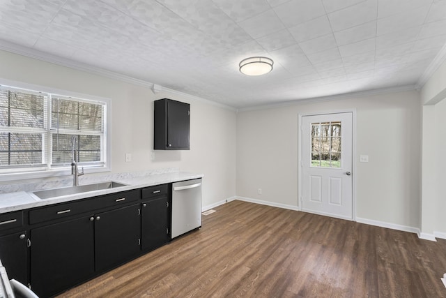 kitchen with dark cabinets, a sink, stainless steel dishwasher, dark wood finished floors, and light countertops