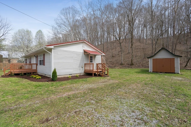 view of green lawn featuring a storage unit, a deck, and an outbuilding