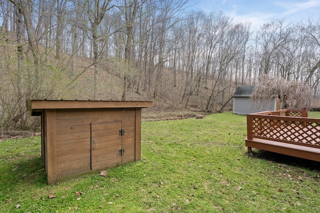 view of grassy yard with a shed, an outdoor structure, and a wooden deck