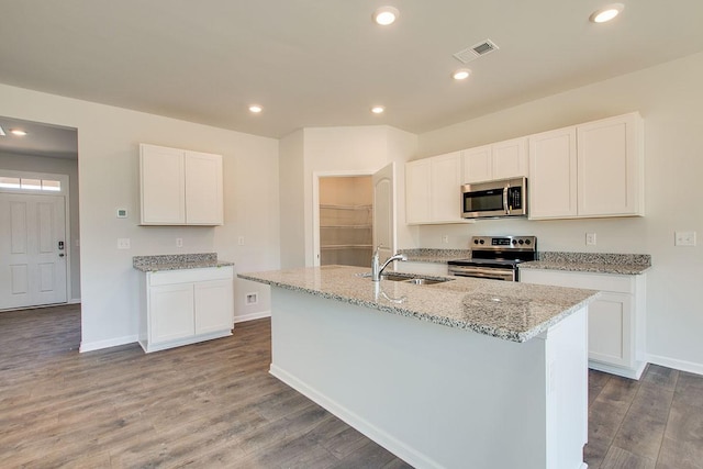 4017 Roane Dr, White House, TN 37188 - kitchen featuring appliances with stainless steel finishes, a sink, light stone countertops, wood finished floors, and a center island with sink