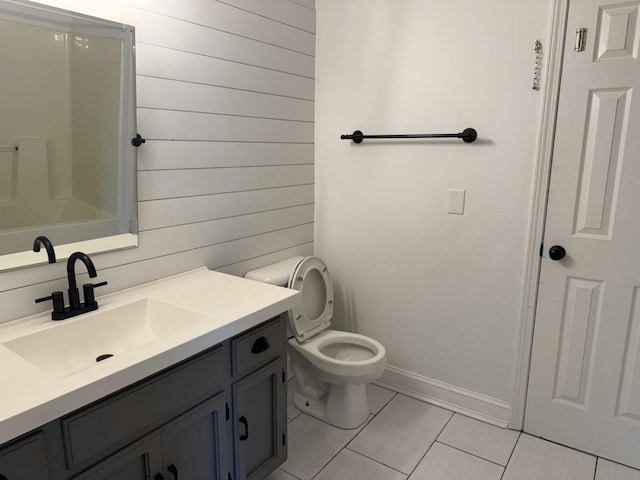 full bath featuring toilet, vanity, tile patterned floors, wooden walls, and baseboards