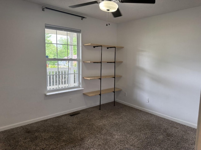 carpeted empty room featuring ceiling fan and baseboards