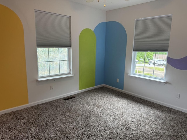 empty room with carpet, arched walkways, baseboards, and ceiling fan
