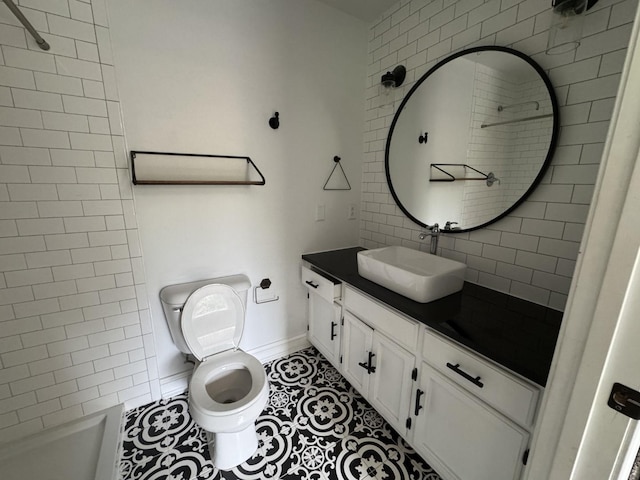bathroom with vanity, toilet, baseboards, a shower, and tile patterned floors