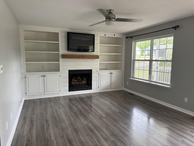 unfurnished living room featuring a textured ceiling, baseboards, a ceiling fan, and dark wood-style flooring