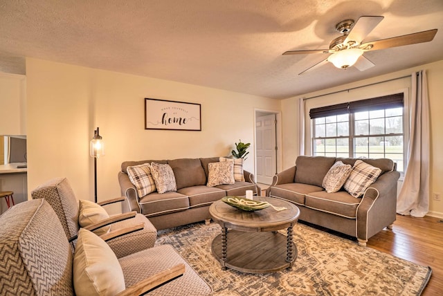 living area with wood finished floors, ceiling fan, a textured ceiling, and baseboards
