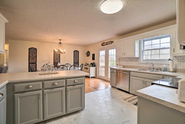 kitchen featuring dishwasher, a sink, gray cabinets, a textured ceiling, and light countertops