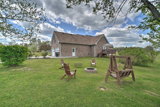 view of grassy yard with a fire pit, a wooden deck, a garage, and stairs