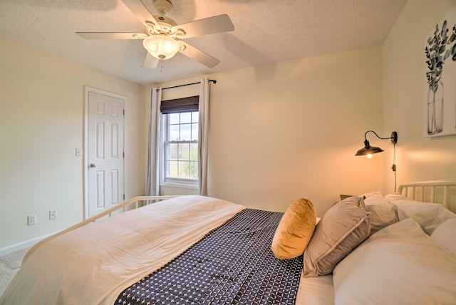 carpeted bedroom featuring baseboards, ceiling fan, and a textured ceiling