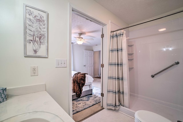 ensuite bathroom featuring a shower with curtain, a ceiling fan, a textured ceiling, toilet, and a sink
