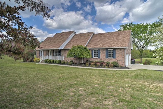 view of front of house featuring a porch, brick siding, a front yard, and driveway