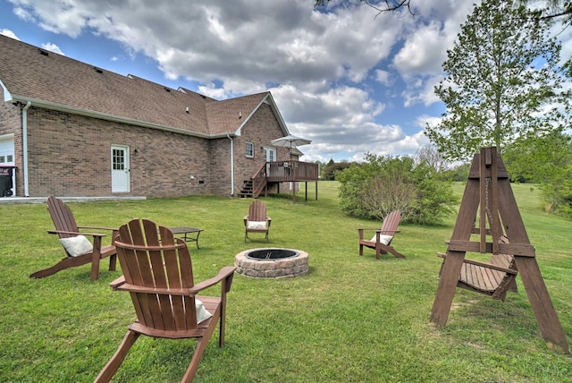 view of green lawn featuring an outdoor fire pit, a deck, and stairway