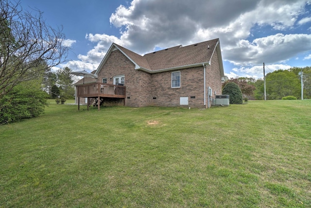rear view of property featuring a deck, brick siding, a yard, and crawl space