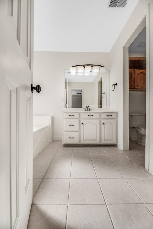 full bathroom with tile patterned flooring, a garden tub, vanity, and toilet