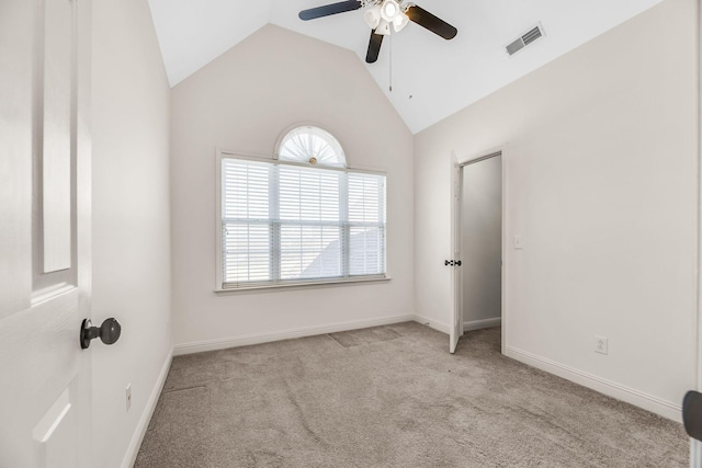 carpeted empty room featuring a ceiling fan, plenty of natural light, vaulted ceiling, and baseboards