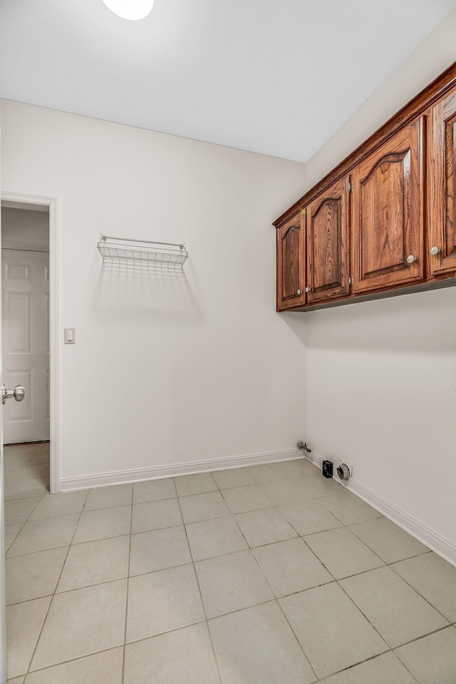 laundry area with cabinet space, baseboards, light tile patterned floors, and gas dryer hookup