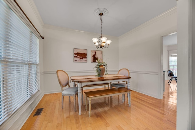dining area featuring a chandelier, crown molding, light wood-style floors, and baseboards