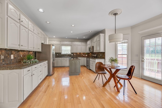 kitchen featuring appliances with stainless steel finishes, a sink, plenty of natural light, dark countertops, and crown molding
