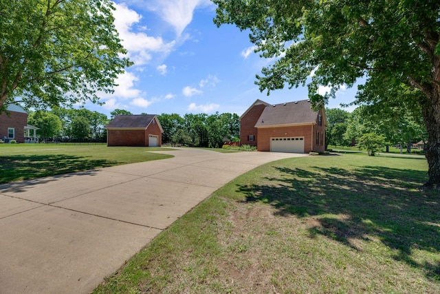 view of front facade featuring brick siding, a front yard, an outdoor structure, and concrete driveway