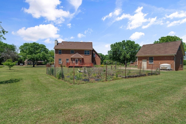 view of green lawn featuring a garden and a deck